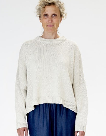 Person wearing a white sweater over a blue skirt on a white background