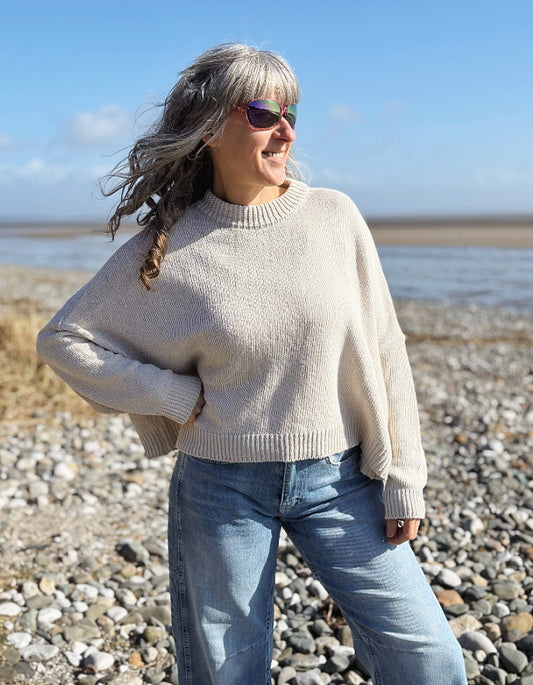 woman wearing a wide fit cotton sweater with jeans on a beach