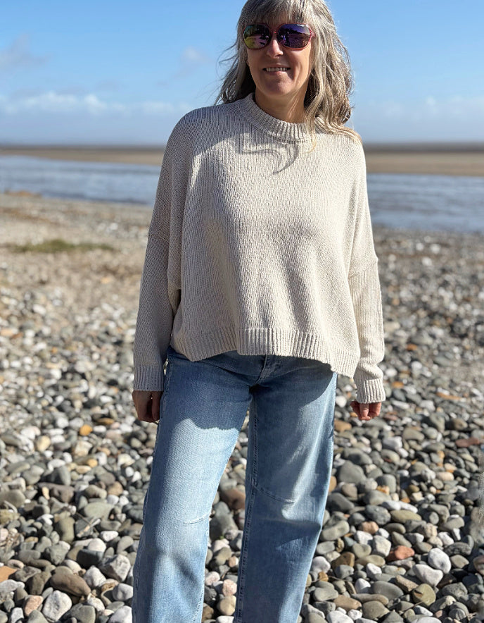 woman wearing a wide fit cotton sweater with jeans on a beach