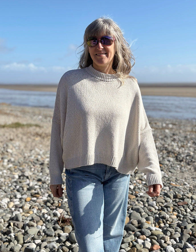 woman wearing a wide fit cotton sweater with jeans on a beach