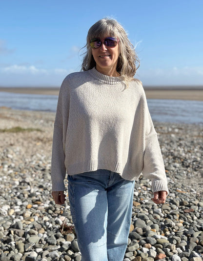 woman wearing a wide fit cotton sweater with jeans on a beach