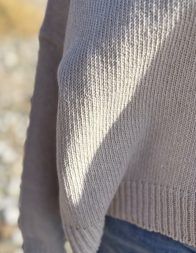 woman wearing a wide fit cotton sweater with jeans on a beach