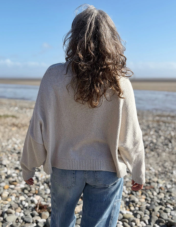 woman wearing a wide fit cotton sweater with jeans on a beach