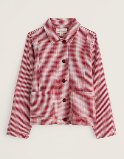 Woman wearing a red and white checkered jacket with a straw hat on a plain background