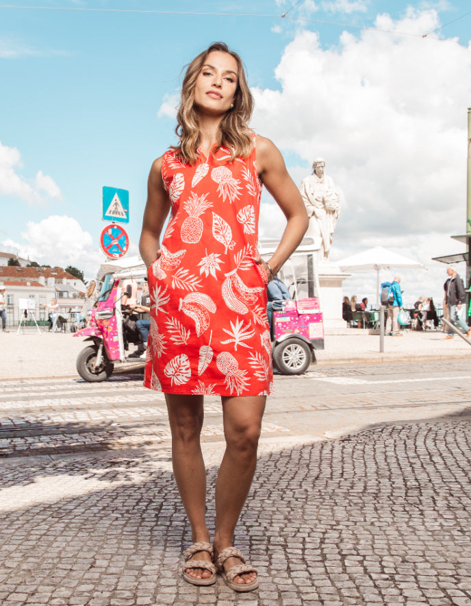 Woman in a red dress with white patterns standing on a street.