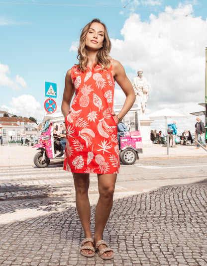 Woman in a red dress with white patterns standing on a street.