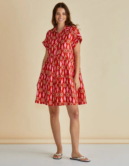 Woman wearing a red patterned dress against a beige background