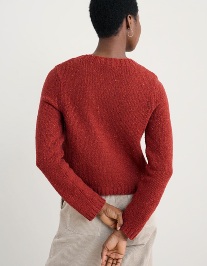 Person wearing a red knitted donegal tweed cardigan with a neutral background