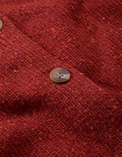Person wearing a red knitted donegal tweed cardigan with a neutral background