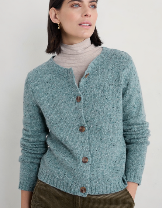 Woman wearing a teal knitted cardigan with brown buttons on a plain background
