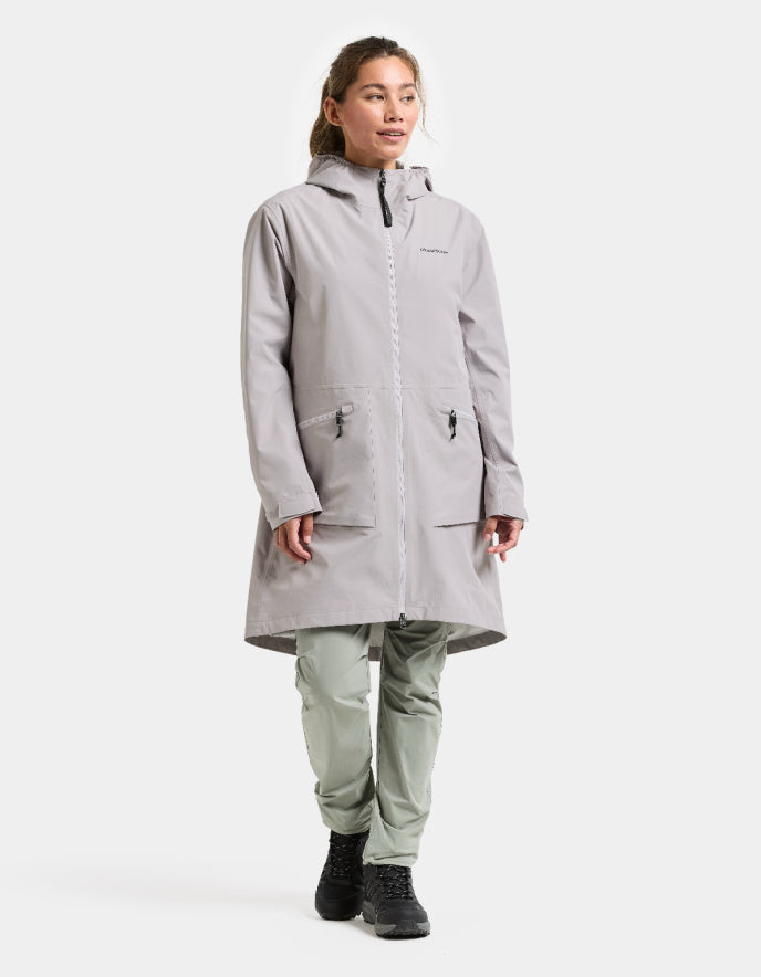 Person wearing a gray raincoat and pants on a white background