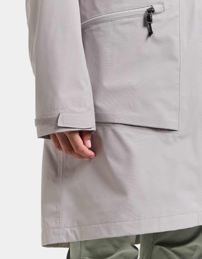 Close-up of a person wearing a light gray raincoat on a white background