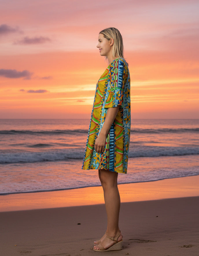 Woman in a colorful dress standing on a beach at sunset