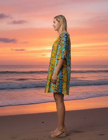 Woman in a colorful dress standing on a beach at sunset