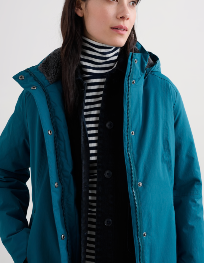 Person wearing a teal raincoat with a hood on a white background