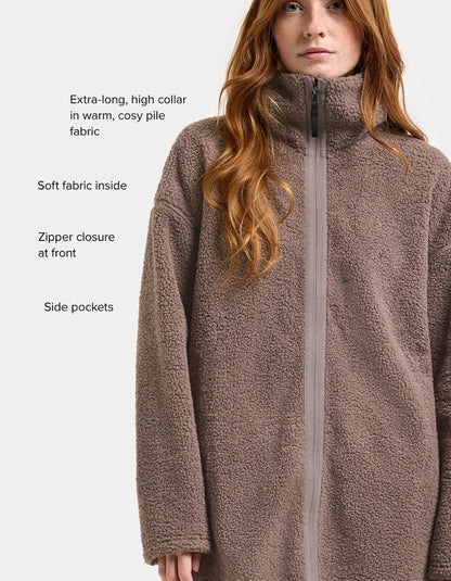 Woman wearing a brown long sherpa pile fleece coat on a white background