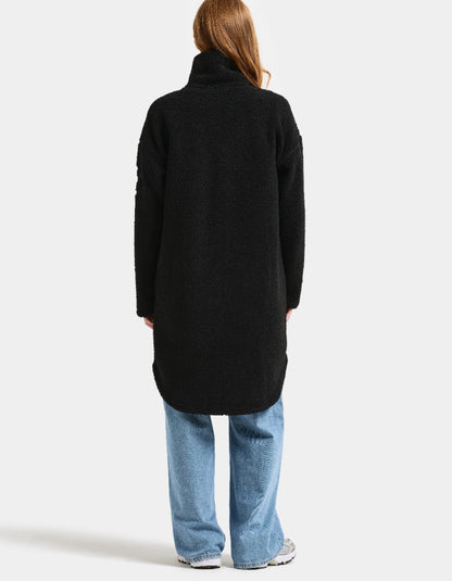 Woman wearing a black sherpa pile fleece coat on a white background