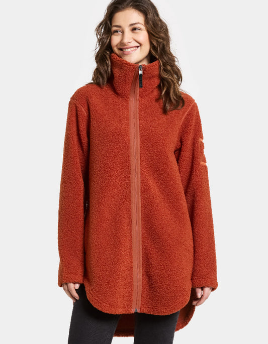 Woman wearing a rust orange sherpa pile fleece  jacket on a white background