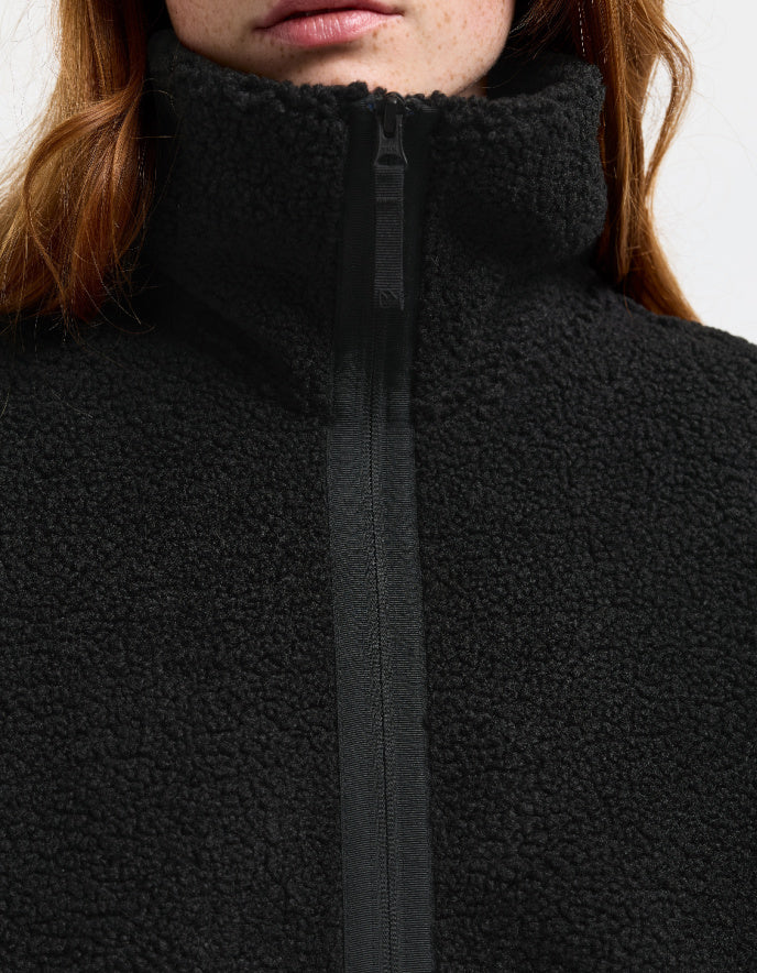 Woman wearing a black sherpa pile fleece coat on a white background