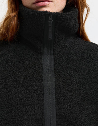 Woman wearing a black sherpa pile fleece coat on a white background