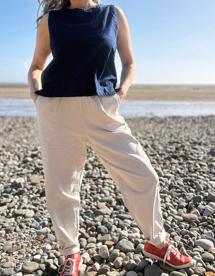 woman wearing natural cotton pants and denim tank on a beach