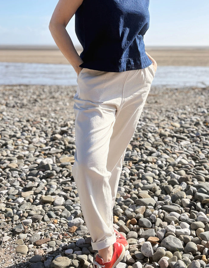 woman wearing natural cotton pants and denim tank on a beach