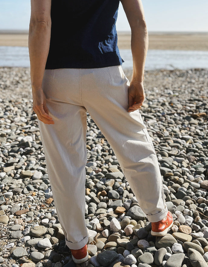 woman wearing natural cotton pants and denim tank on a beach