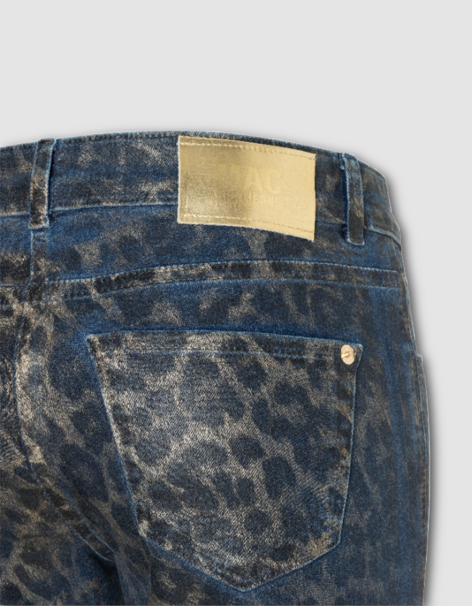 Close-up of blue jeans with a leopard print pocket and beige label on a light gray background
