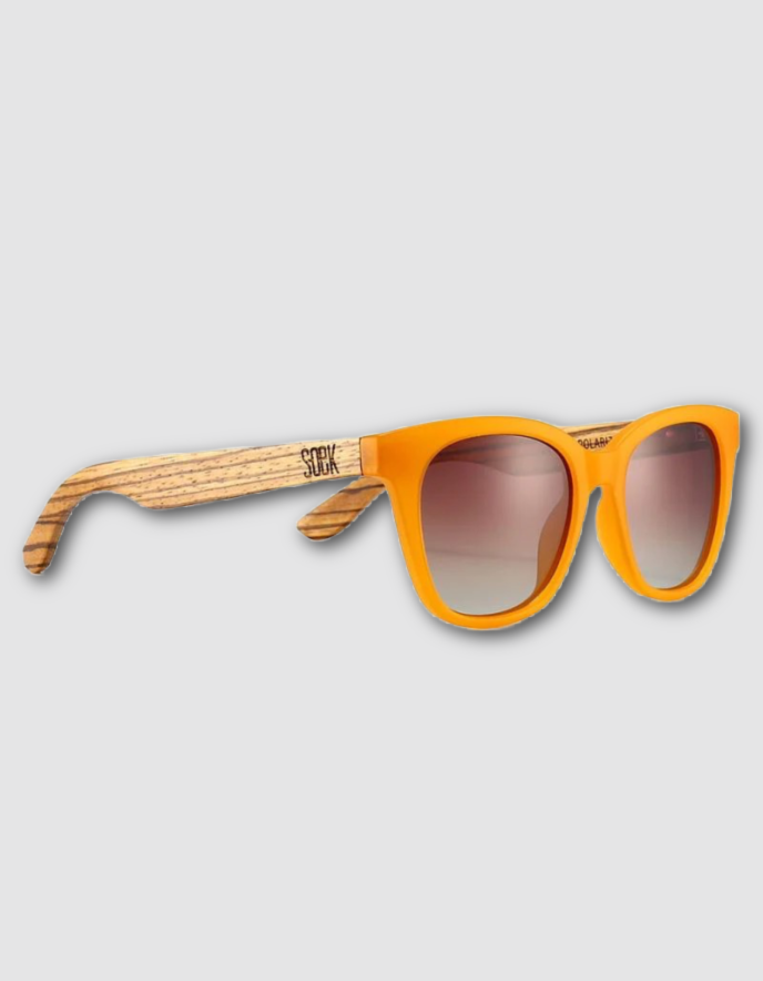 Orange acetate sunglasses with a natural wood grain temple arm and gradient brown lenses, shown on a light gray background.
