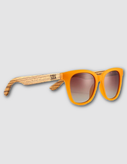 Orange acetate sunglasses with a natural wood grain temple arm and gradient brown lenses, shown on a light gray background.