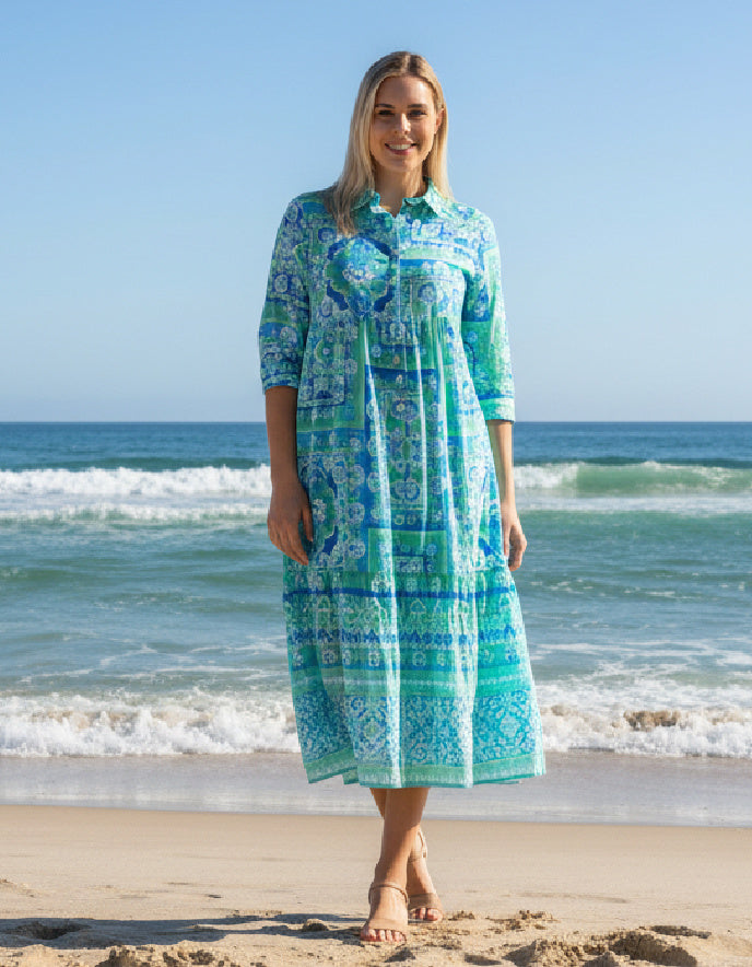 a woman wearing a turquoise layered cotton shirt dress with sleeves on a beach