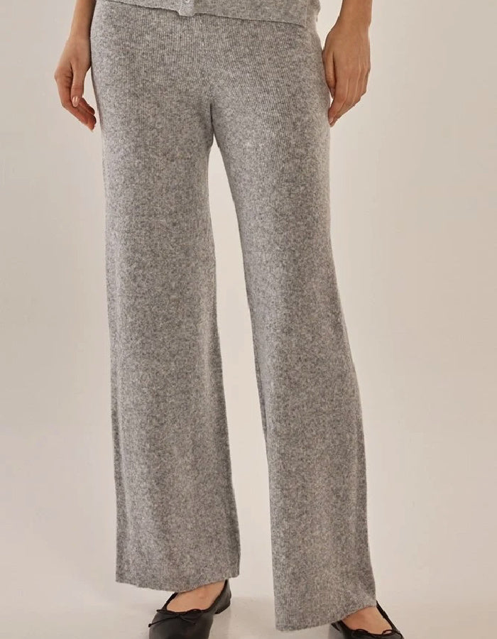 A person wearing heather gray knit wide-leg pants with a matching top partially visible, photographed against a plain light beige studio background.