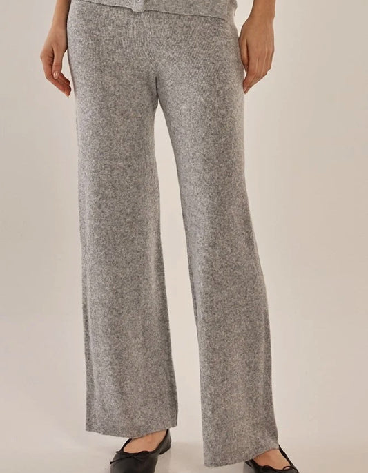 A person wearing heather gray knit wide-leg pants with a matching top partially visible, photographed against a plain light beige studio background.