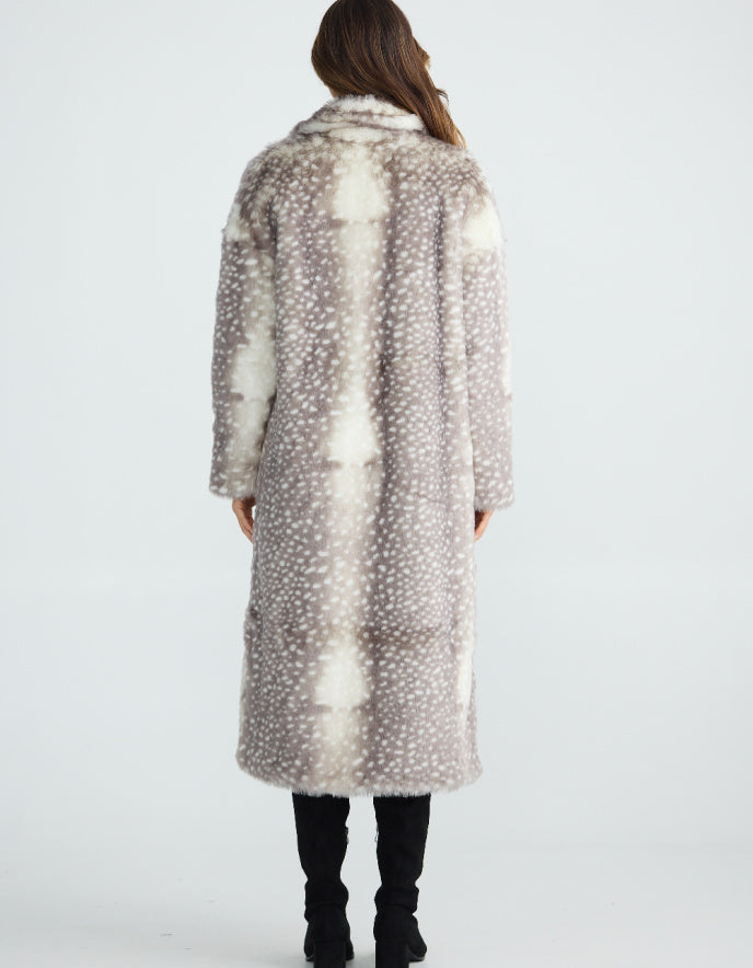 Woman wearing a long, patterned faux fur grey Bambi coat standing on a plain background