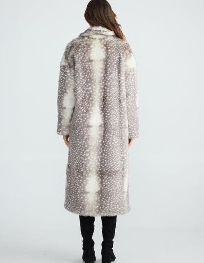 Woman wearing a long, patterned faux fur grey Bambi coat standing on a plain background