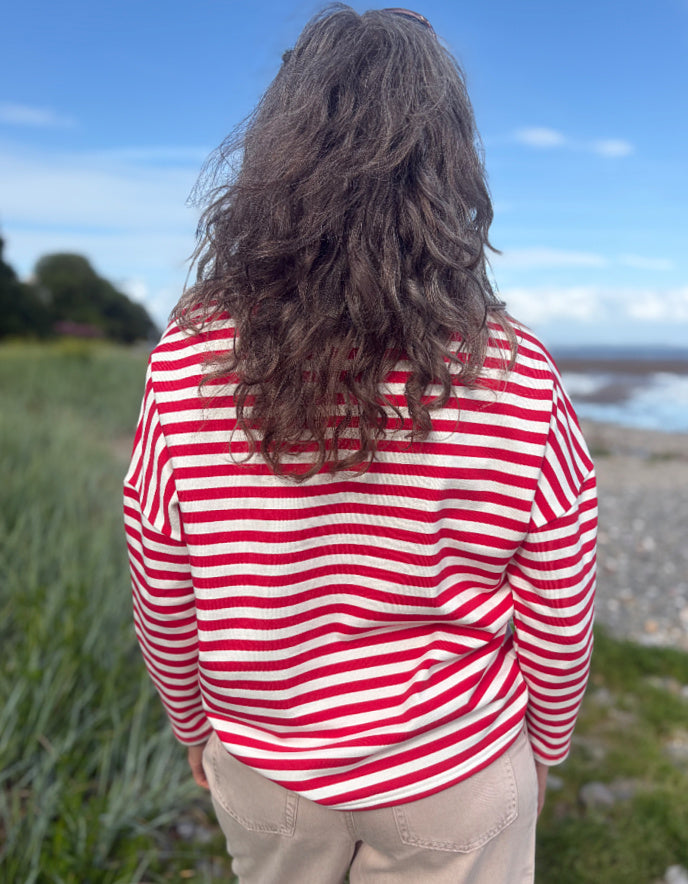 Person wearing a red and white striped shirt standing outdoors with a scenic background