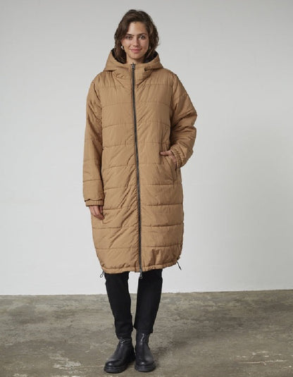 Woman wearing a black and beige reversible winter coat against a plain background