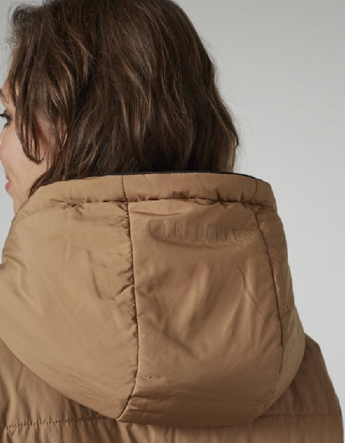 Close-up of a person wearing a brown puffer jacket with a brand logo on a plain background