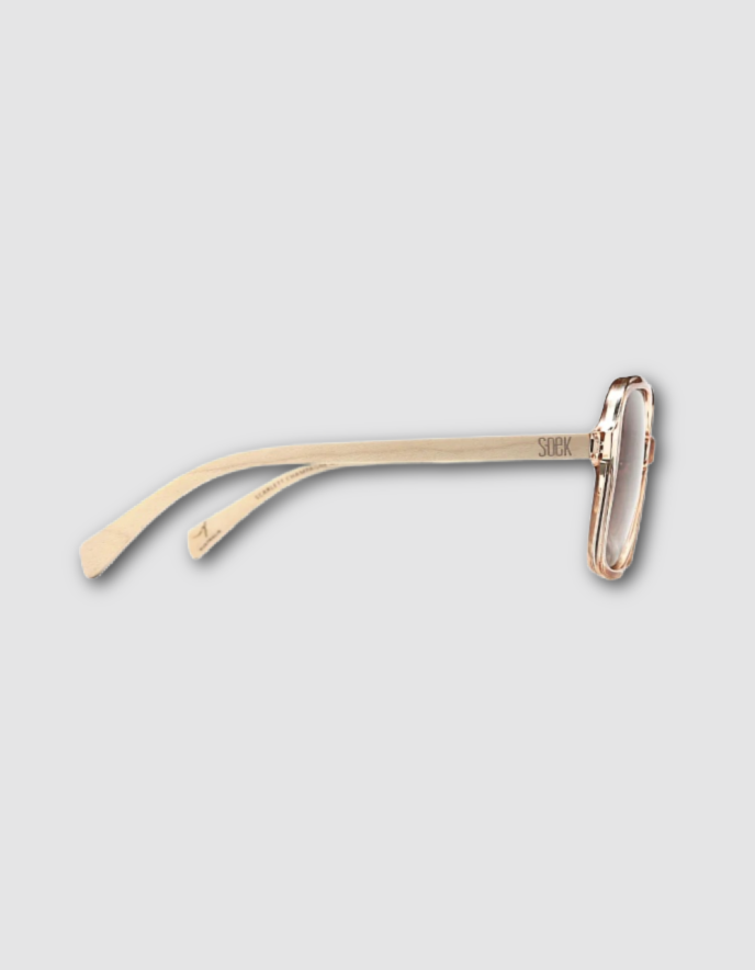 A pair of minimalist champagne framed sunglasses with a unique wooden arms and slim temples, shown on a light grey background.