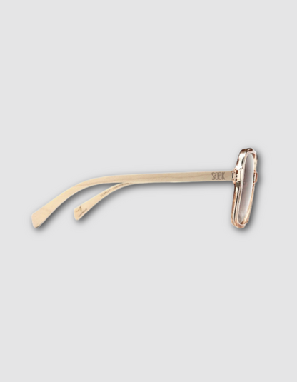 A pair of minimalist champagne framed sunglasses with a unique wooden arms and slim temples, shown on a light grey background.