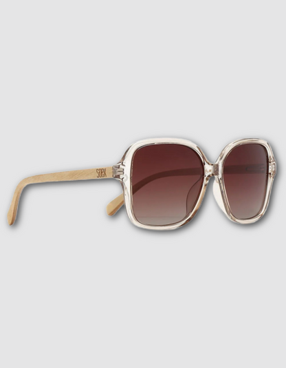 Oversized square sunglasses with a translucent light beige frame, brown gradient lenses, and light temples on a light grey background.