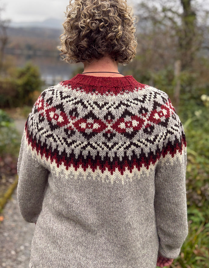Person wearing a patterned sweater with a scenic background