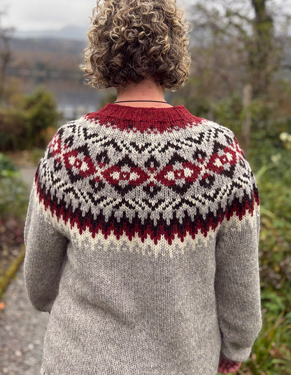 Person wearing a patterned sweater with a scenic background