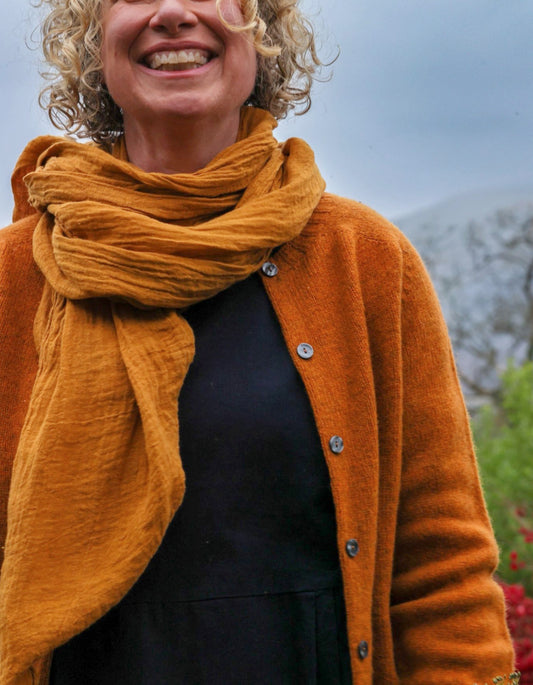 Person wearing an orange cardigan and yellow scarf with a blurred background