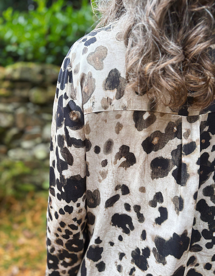 Person wearing a leopard print shirt with a blurred natural background