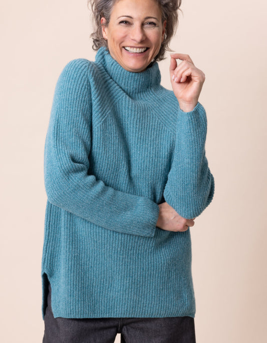 Woman wearing a blue sweater against a beige background