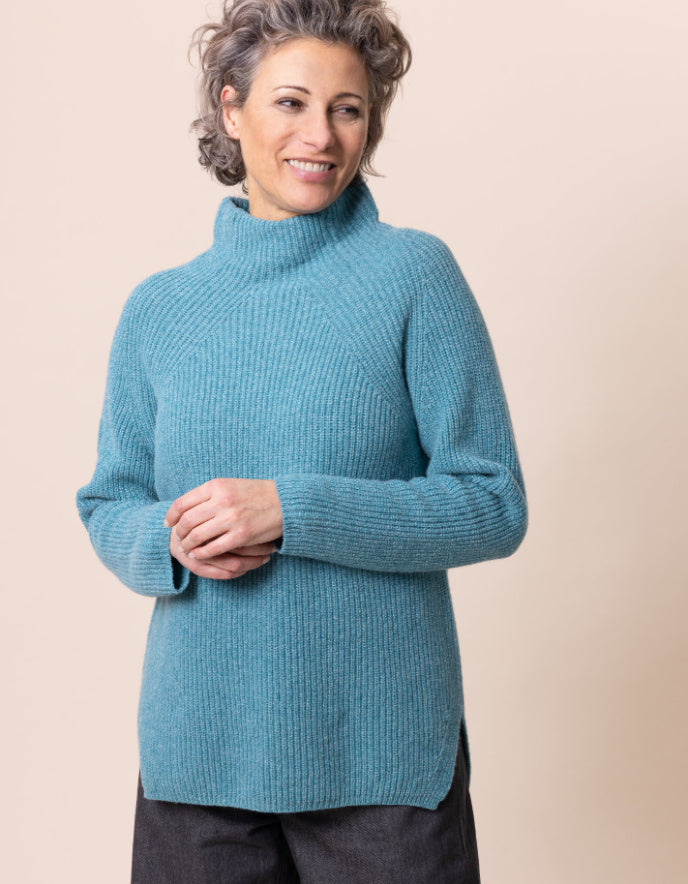 Woman wearing a blue sweater against a beige background