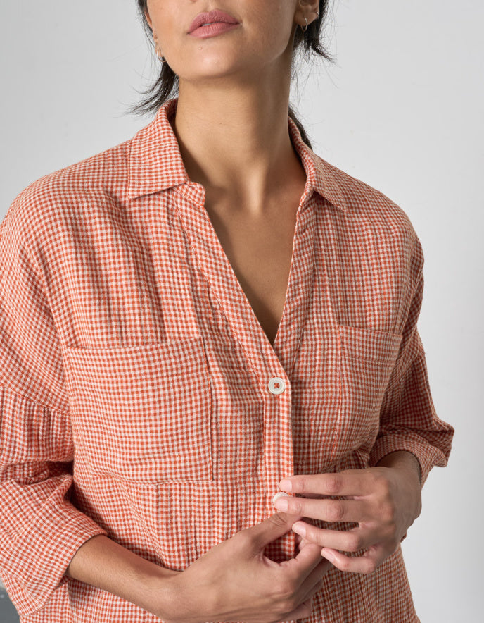 Woman wearing an orange checkered outfit standing indoors