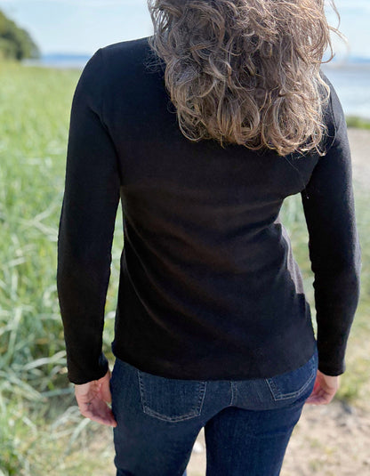 Person wearing a black long-sleeve shirt with a blurred natural background