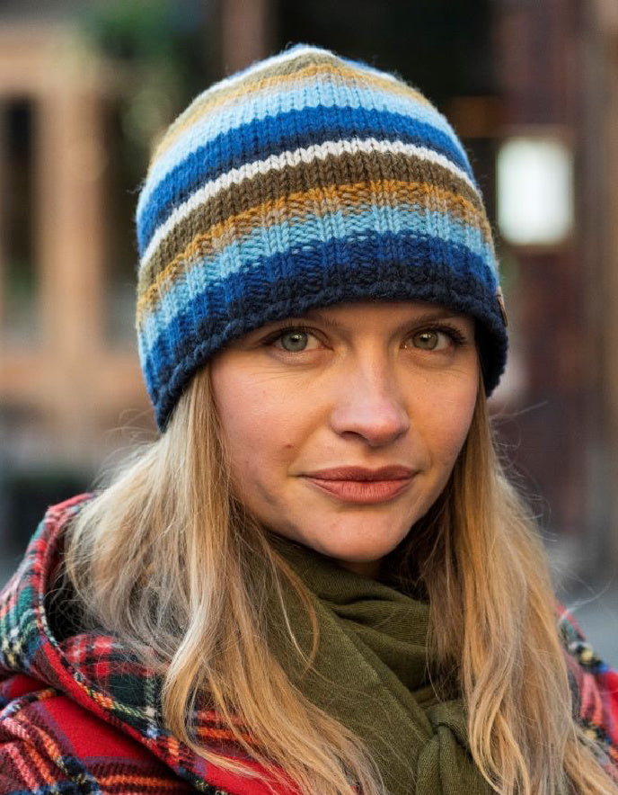 Person wearing a striped knit beanie with a blurred background